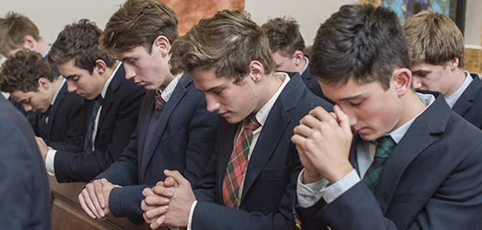 Catholic school boys at the traditional Catholic boarding school Gregory the Great kneel in a pew at Mass.